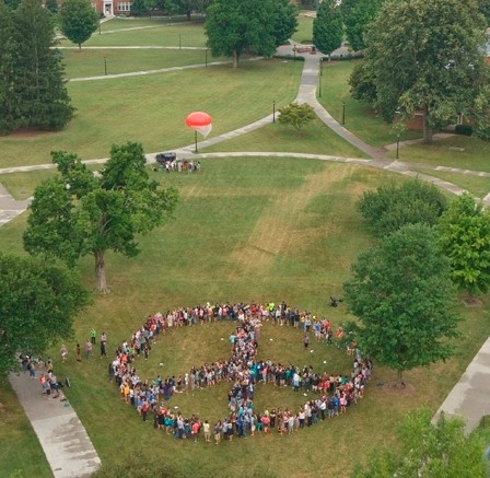 Students taking part in this year's Governor's School join together to form a peace sign as they sing John Lennon's "Give Peace A Chance" on the main lawn.