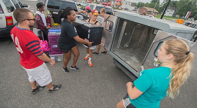 Members of the RU Swim Club and a member of the RU Facilities division move items onto a facilities buggy to be moved to the residence halls as they help the family of Arial Johnson in the move in process.