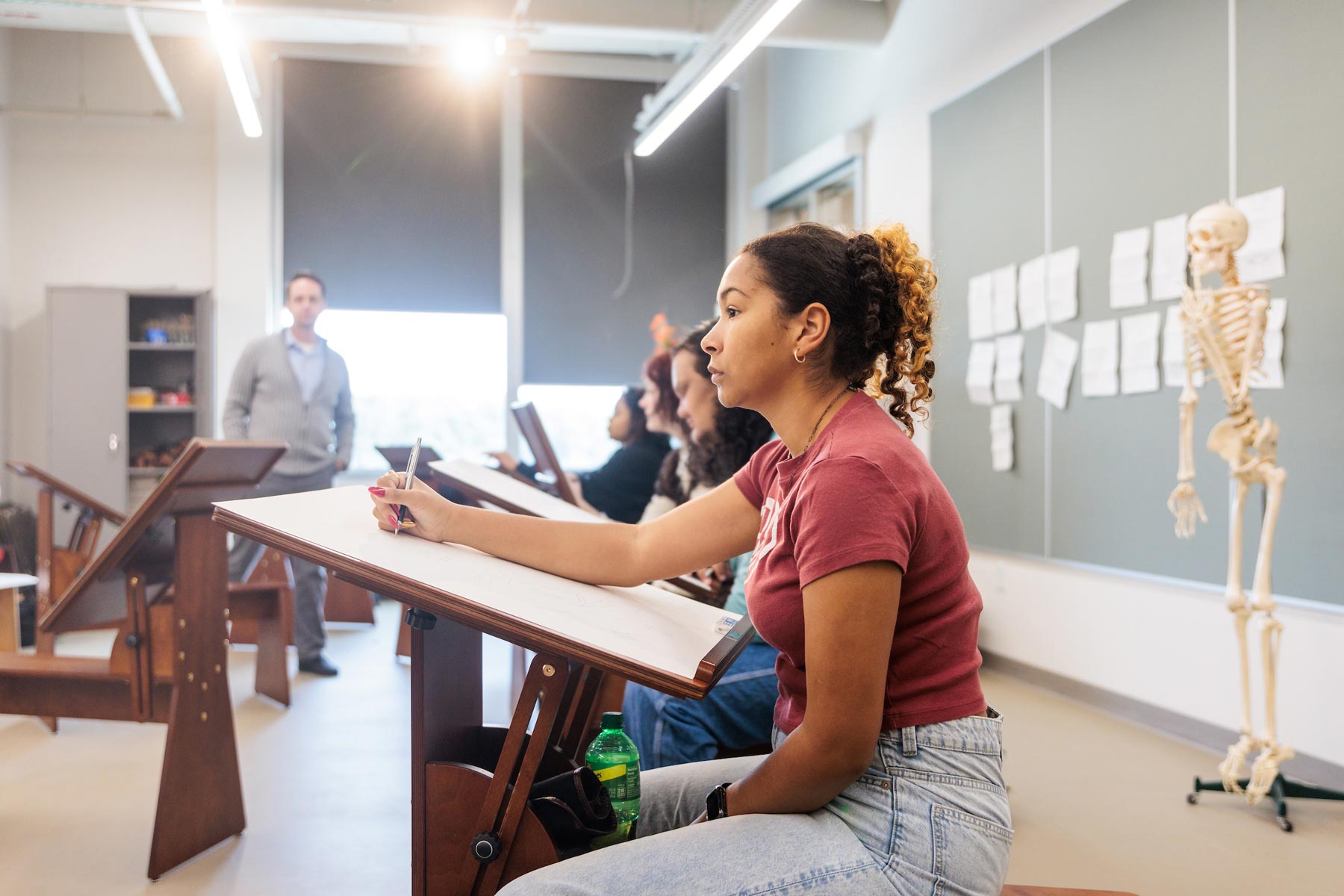 students in a classroom with a professor observing nearby