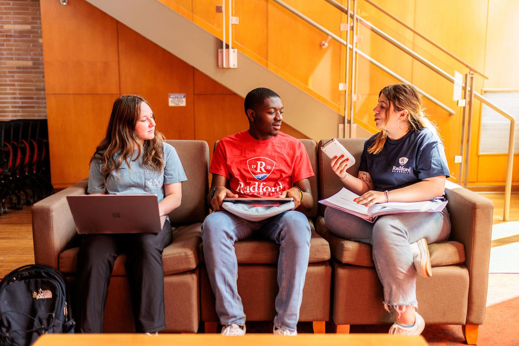 students sitting on chairs with laptops talking