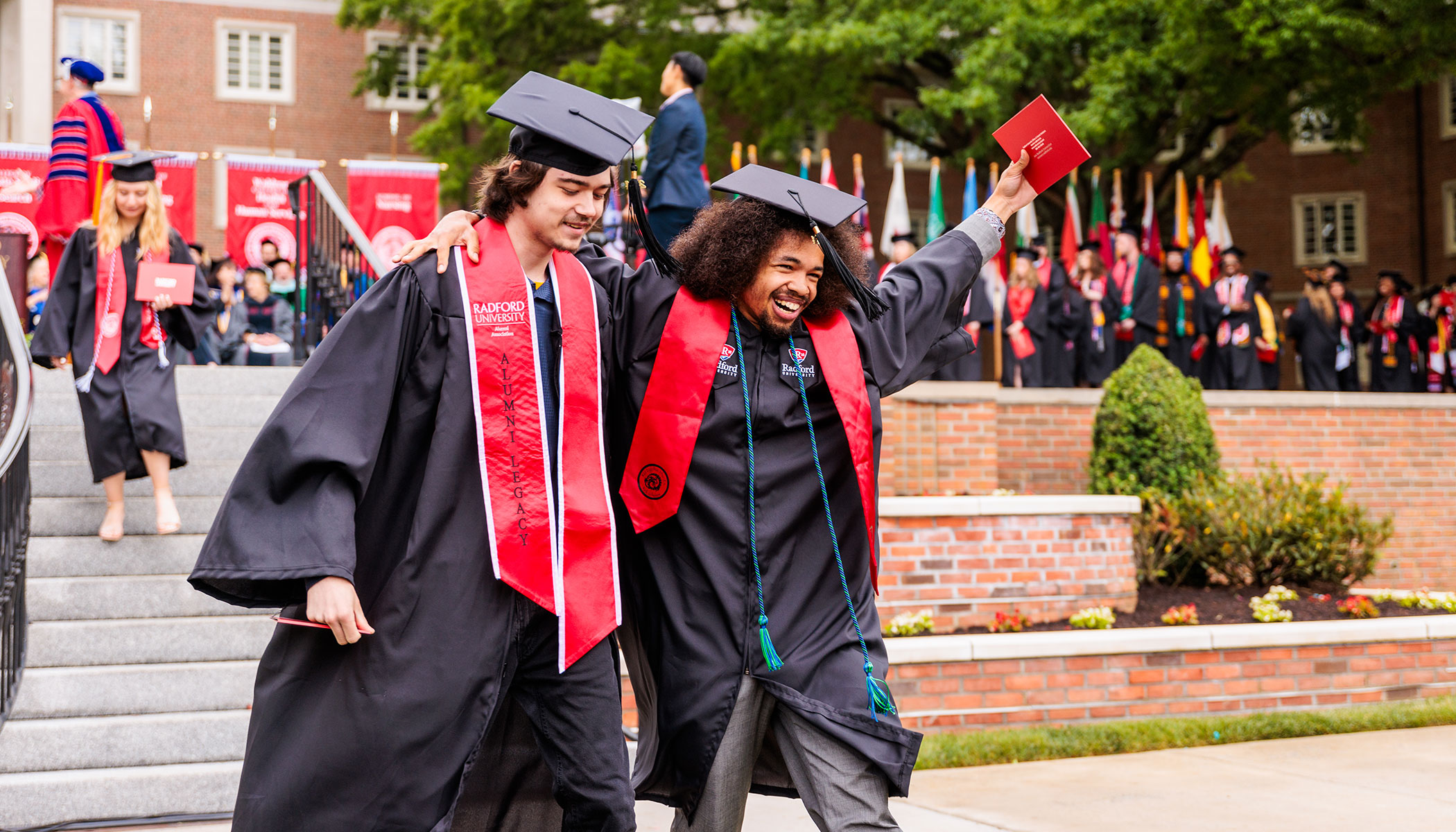 Students celebrating with excitement after crossing the commencement stage.