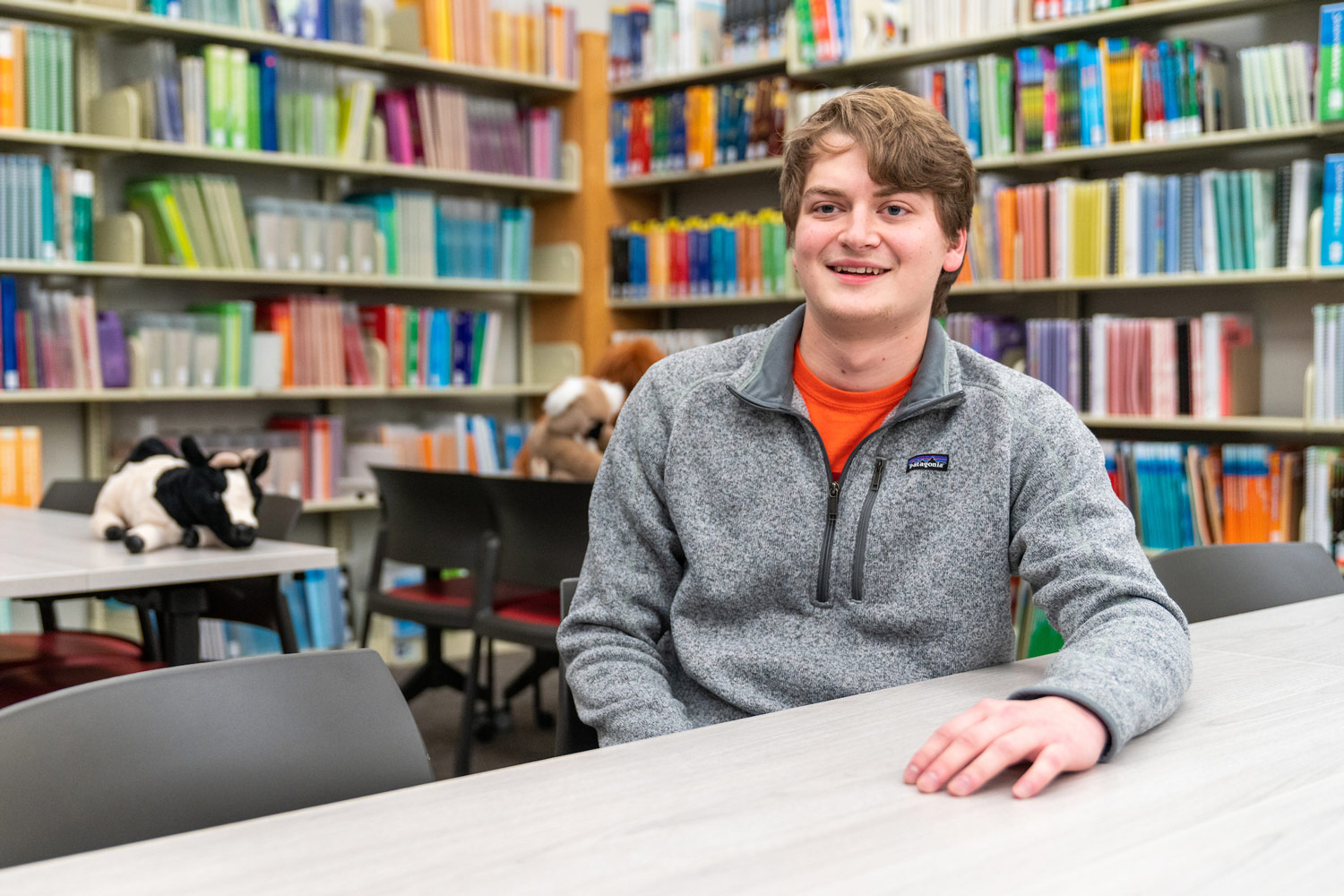 male student in library with books on shelves behind him