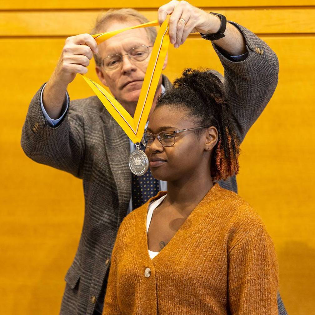Faculty member placing an Honors Medallion on a graduating Honors student.