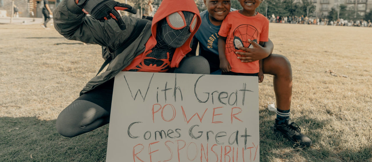 young children wearing spiderman outfits holding a sign that reads 'with great power comes great responsibility'