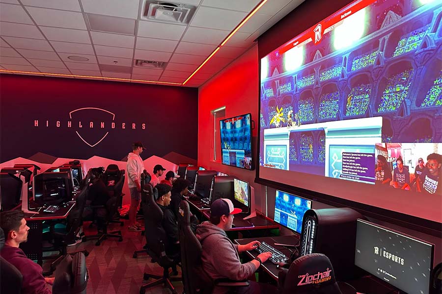 A room full of Radford students engage in computer games, which are displayed on a large screen above them.