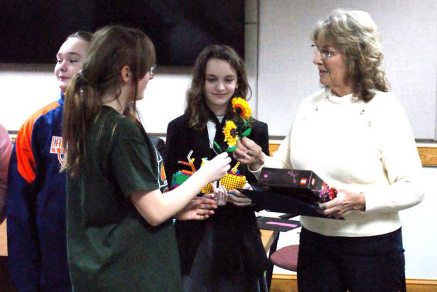 A teacher receives a flower from a student. 