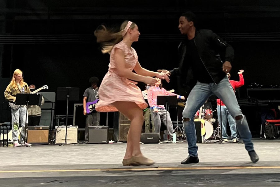 Two dance majors perform onstage before a small band of musicians.