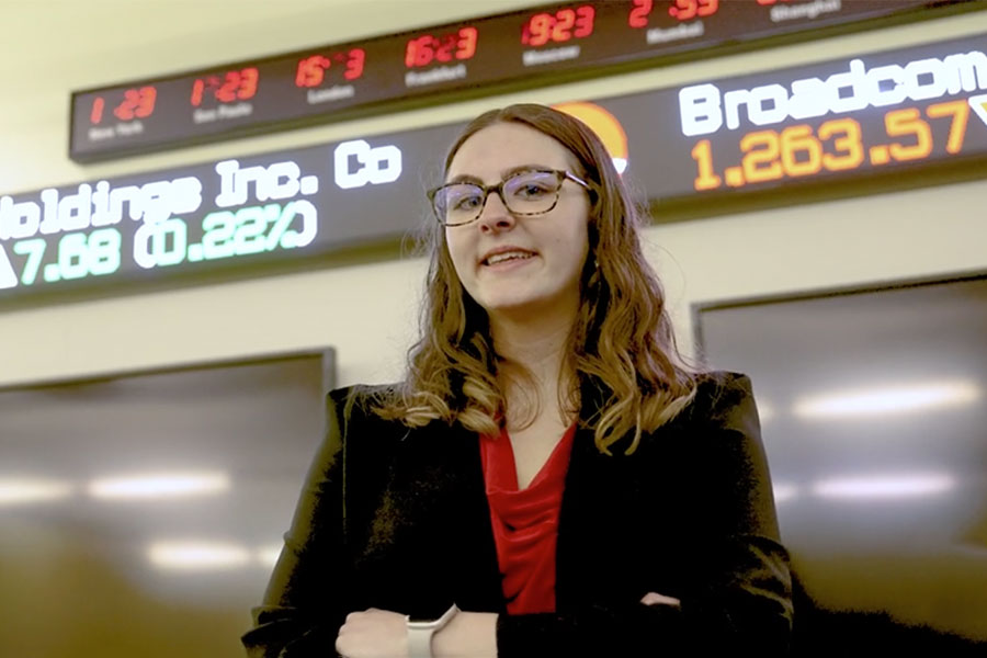 Ariana Rieder standing in front of the scrolling stock numbers in Kyle Hall