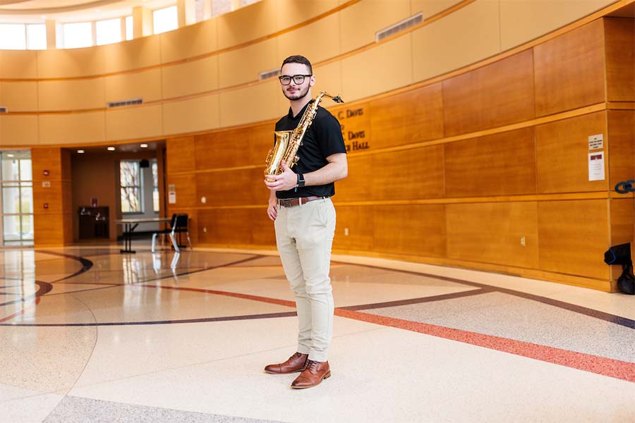 Student holding saxophone, standing in the lobby of Radford