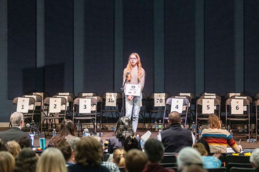 high school student participates in spelling bee on campus
