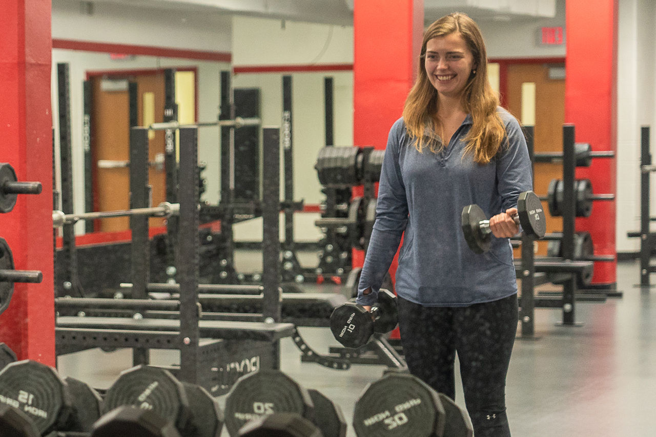 student lifting weight in gym