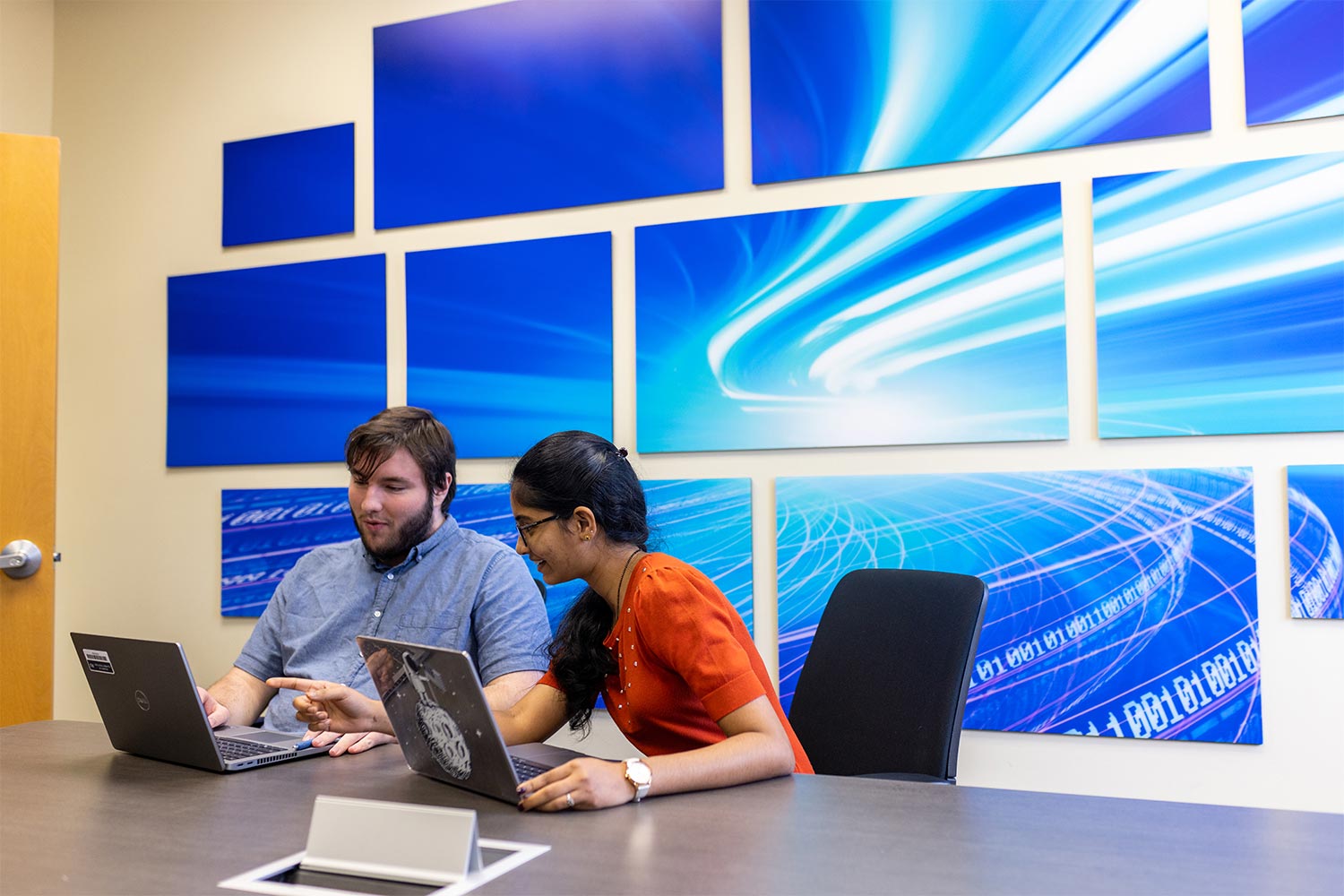 two students in a boardroom with laptop