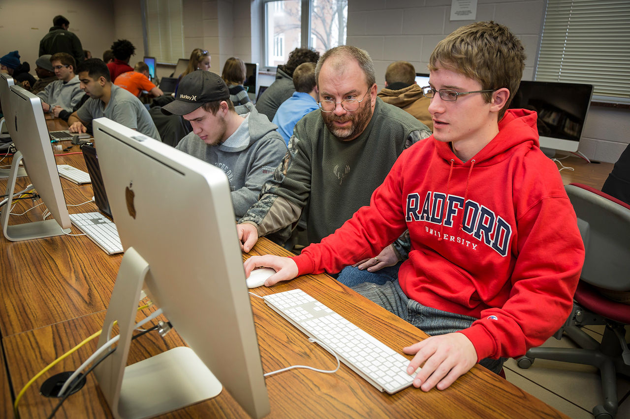 student and instructor in a computer lab looking at a computer together