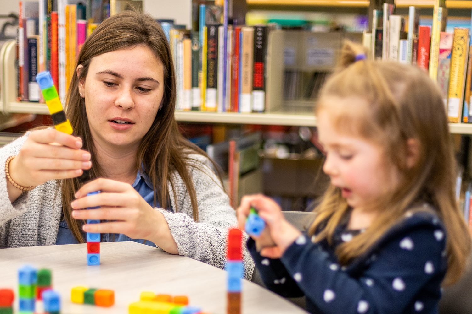 teacher building blocks with young student