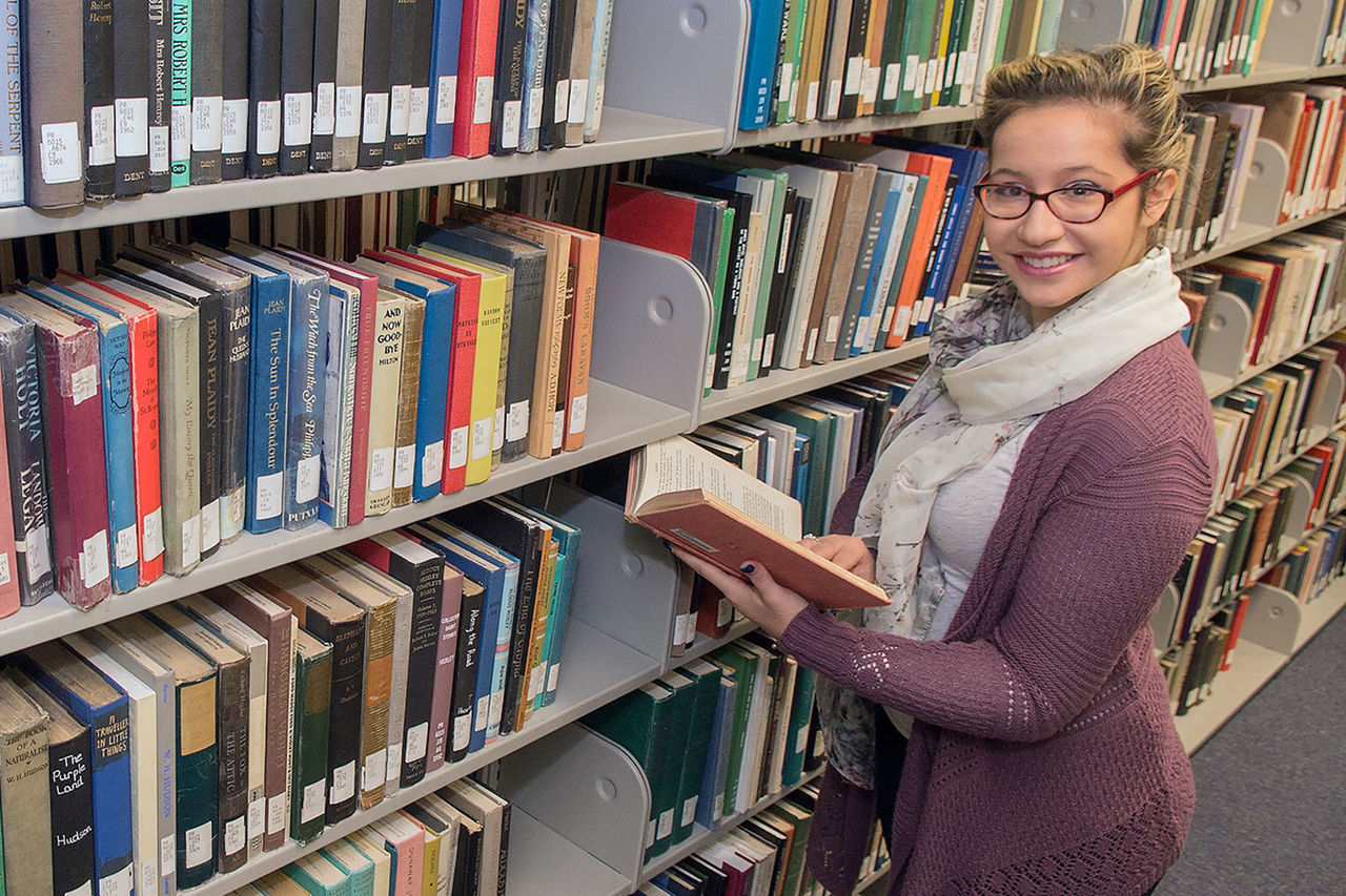 student with a book in the library