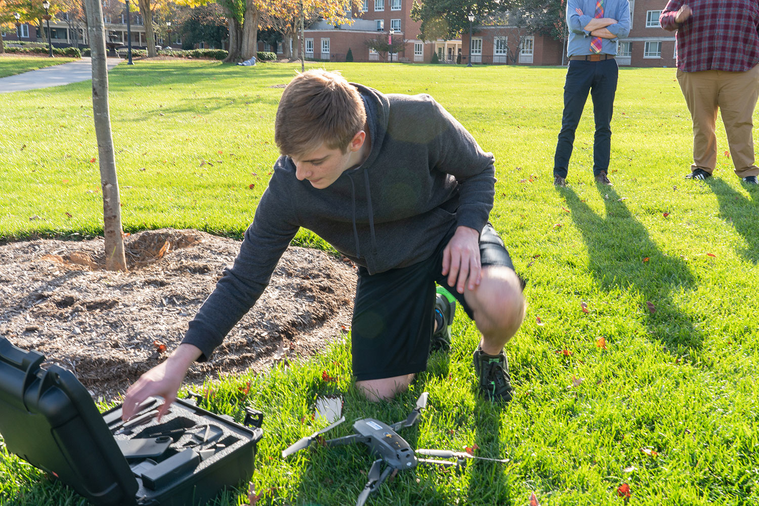 student kneeling on the grass reaching into a toolbox