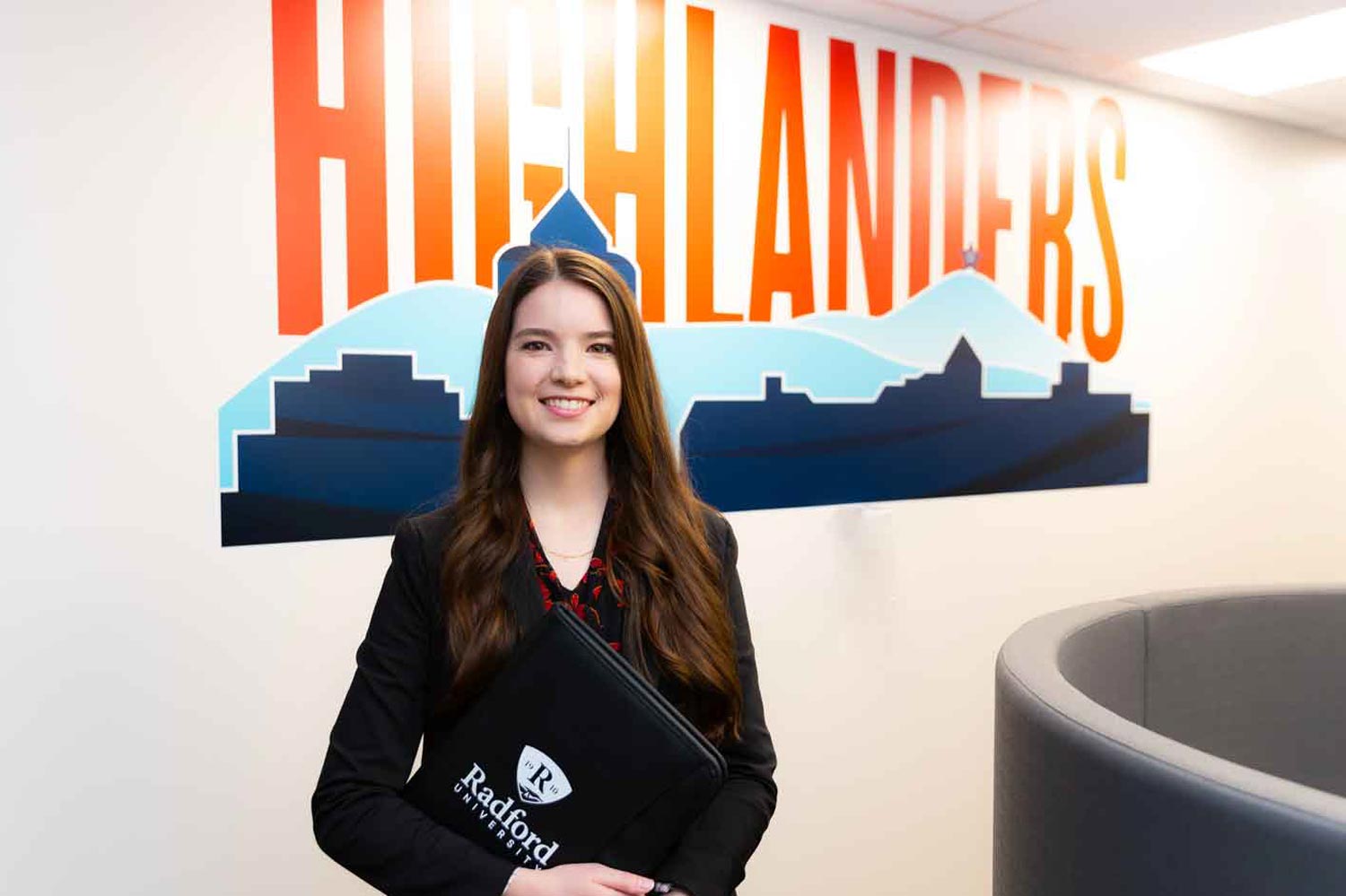 Student in business attire holding padfolio in professional setting
