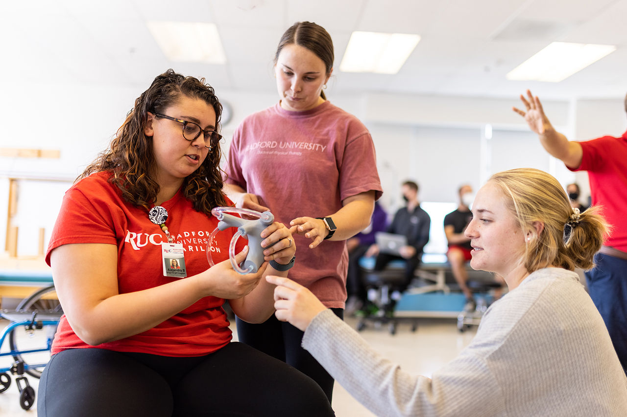 physical therapy students gathered looking at a tool used for hand therapy