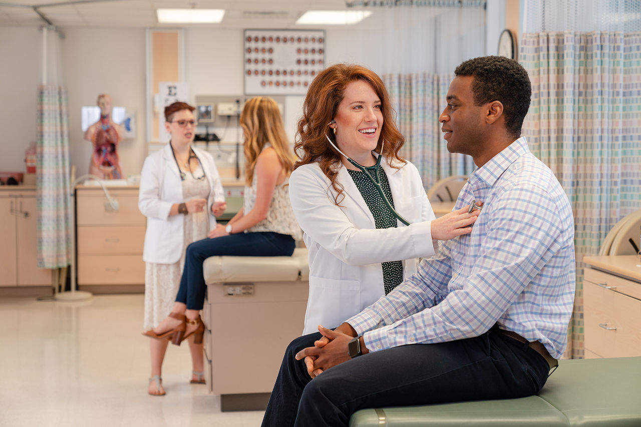 studnet doctor using a stethoscope on a patient to hear their heartbeat