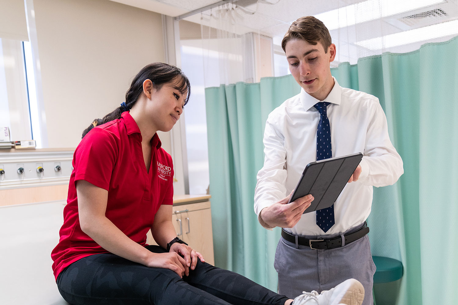 science student showing a patient something on an ipad