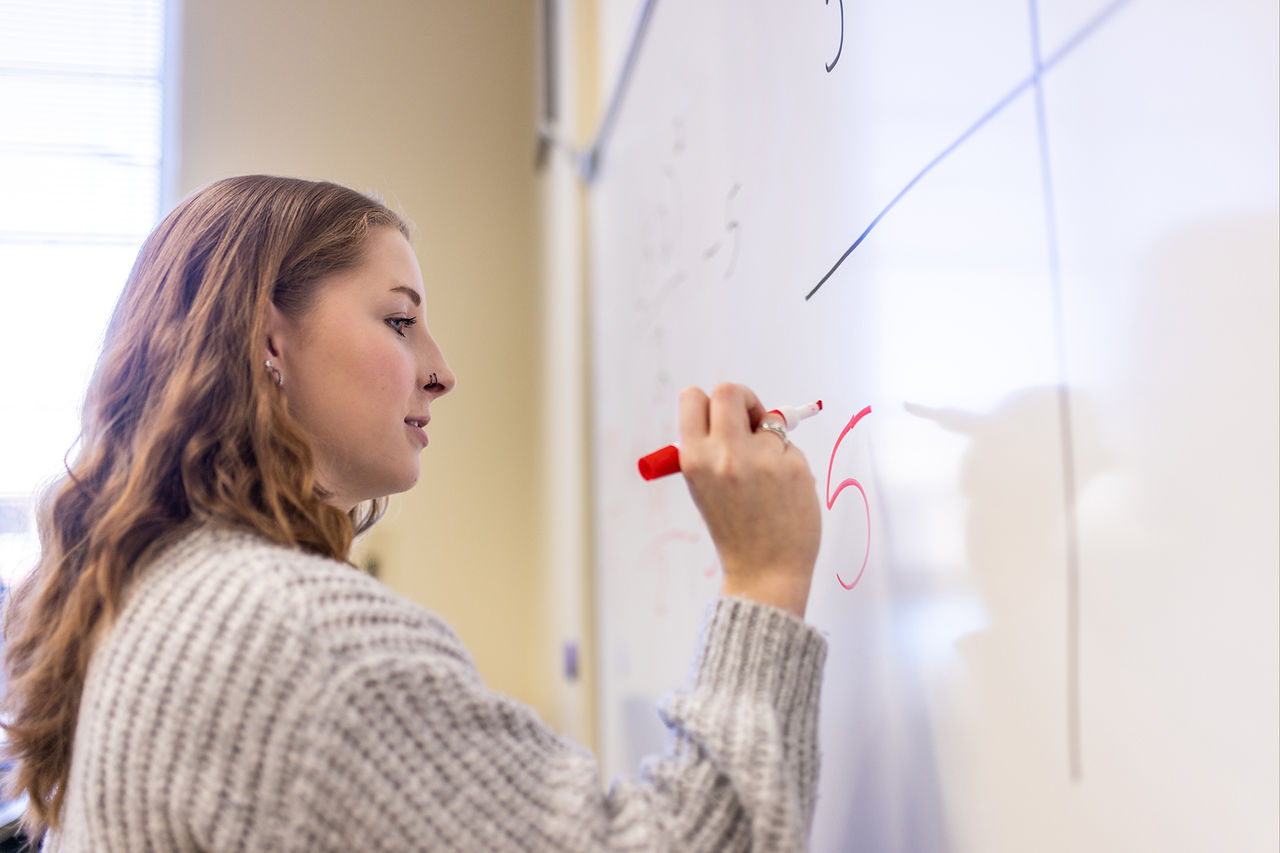 student writing on whiteboard