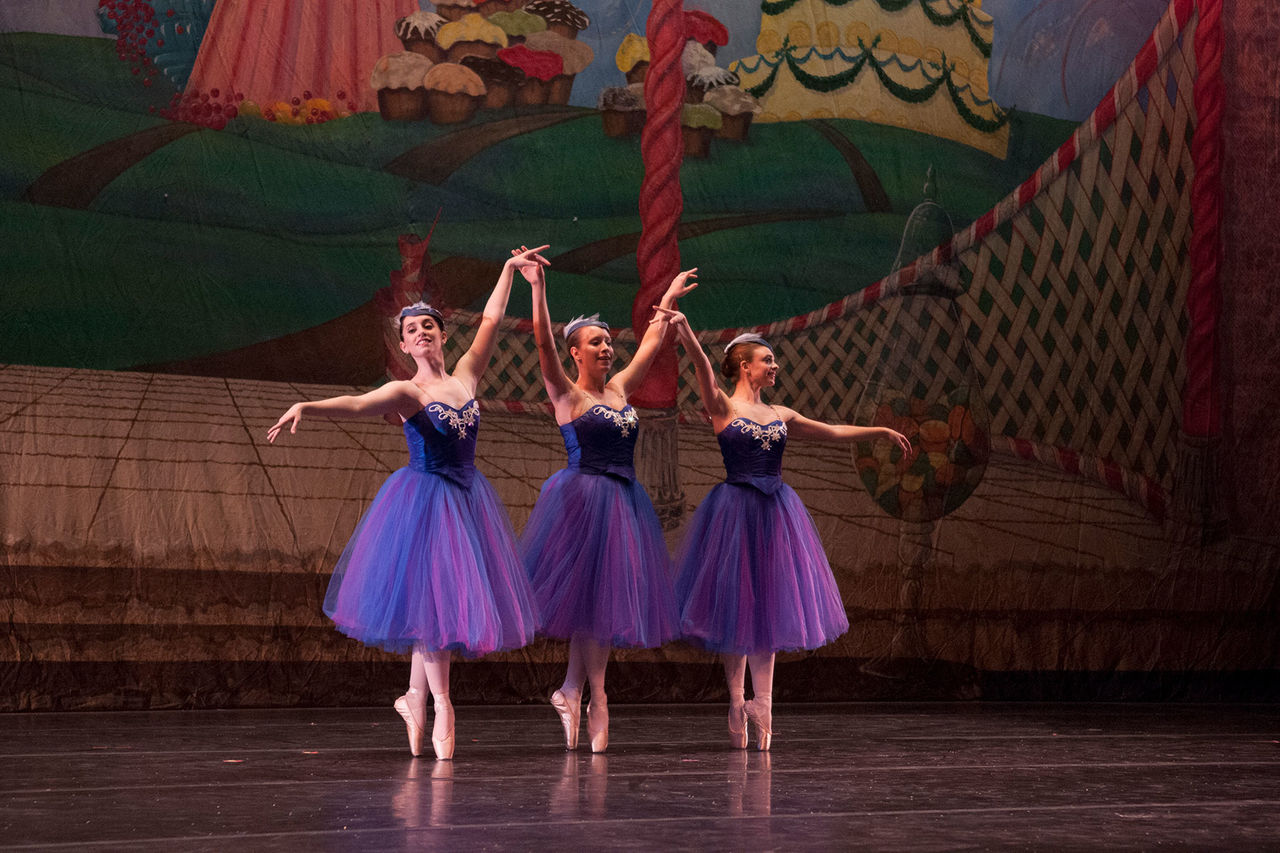 ballet dancers in purple dresses on a stage, dancing