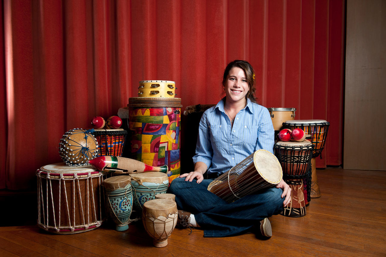 a female sitting with drums around her