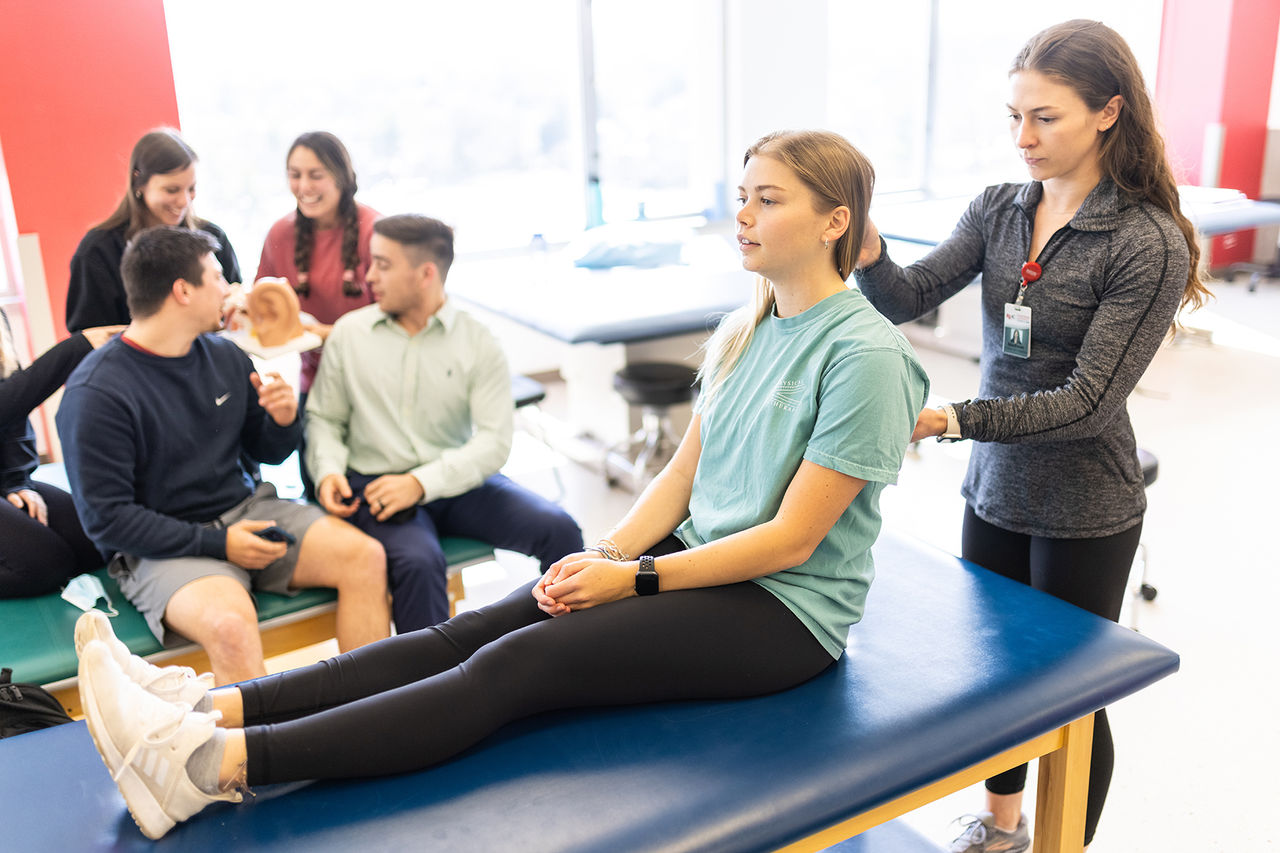a patient sitting upright on a foam table while the radford student adjusts her back and neck