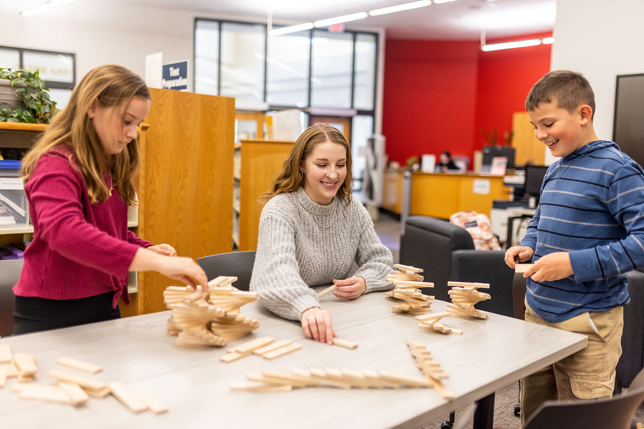 students at a table balancing small wooden pieces into twisted towers