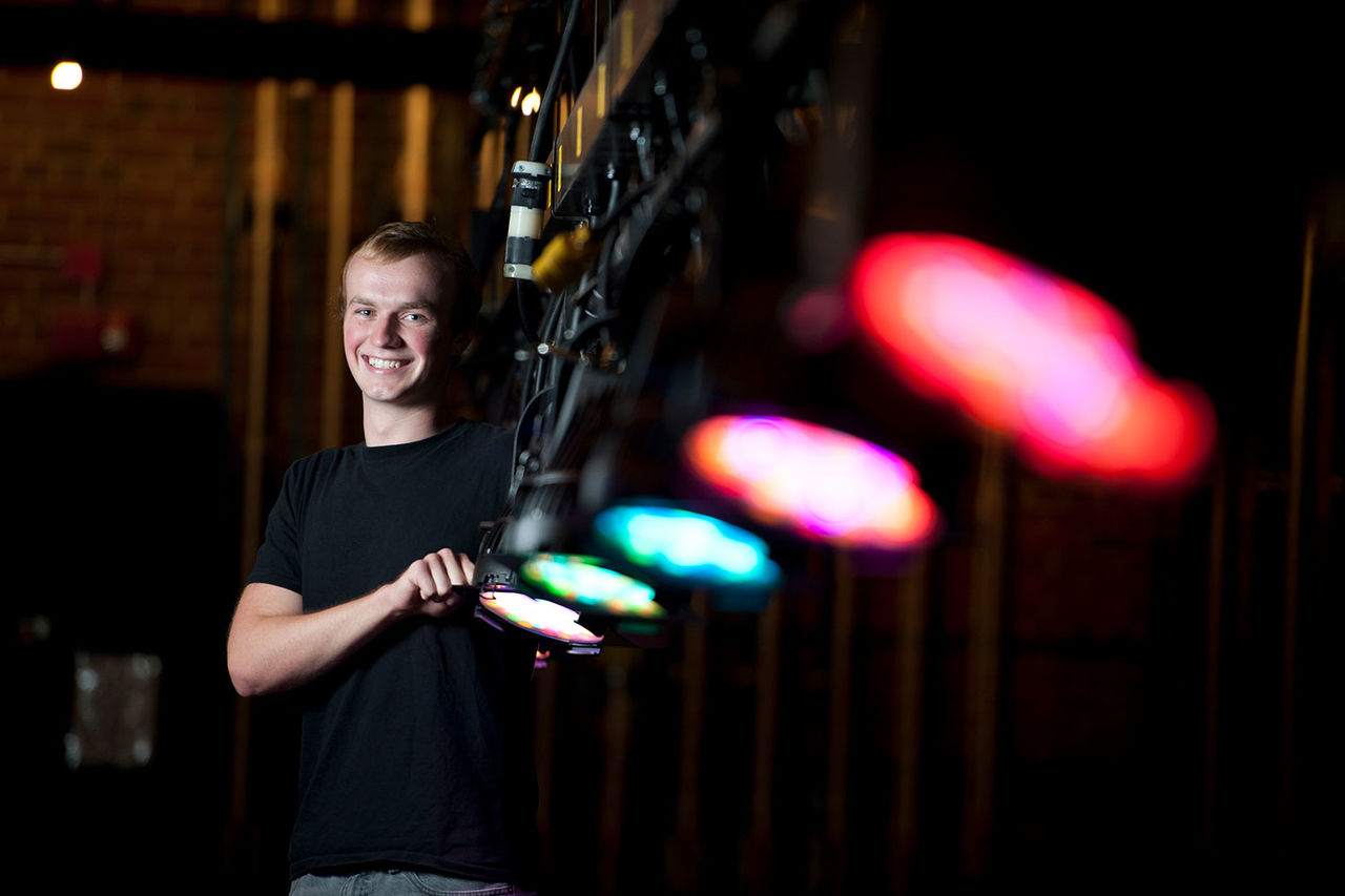 student standing beside stage lights 