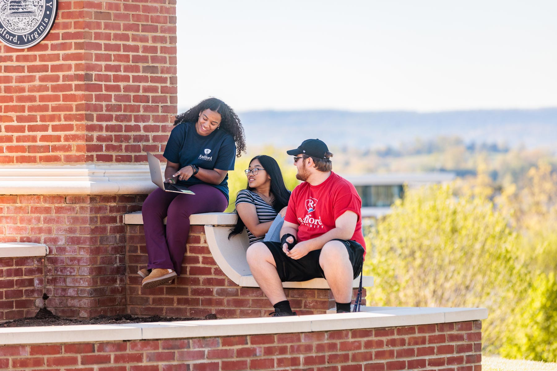 Students sitting and talking on wall on main campus