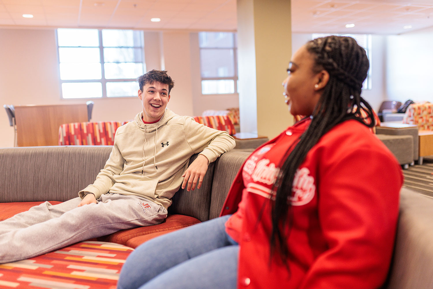 Two students sitting and chatting in a lounge area.